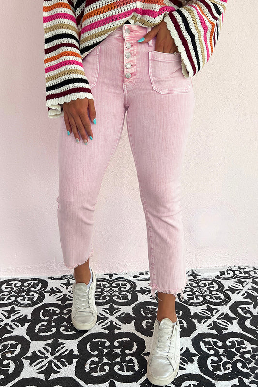 Model wearing high-waisted apricot pink crop jeans with multiple buttons and a raw edge, paired with black heels.