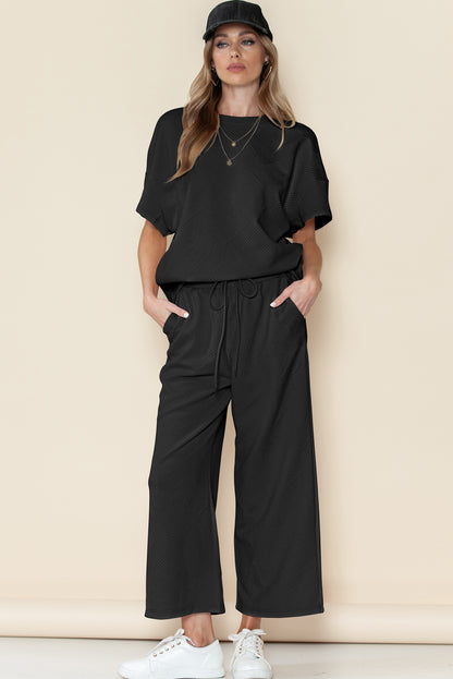 Black textured T-shirt and drawstring pants set styled for lounging at home.