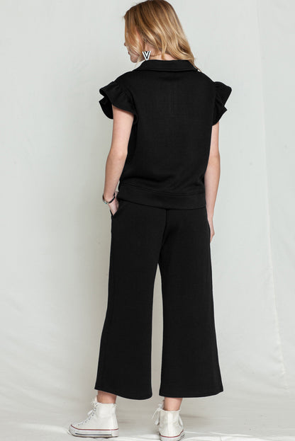 Close-up of black textured fabric on the ruffle cap sleeve top and wide-leg pants set.