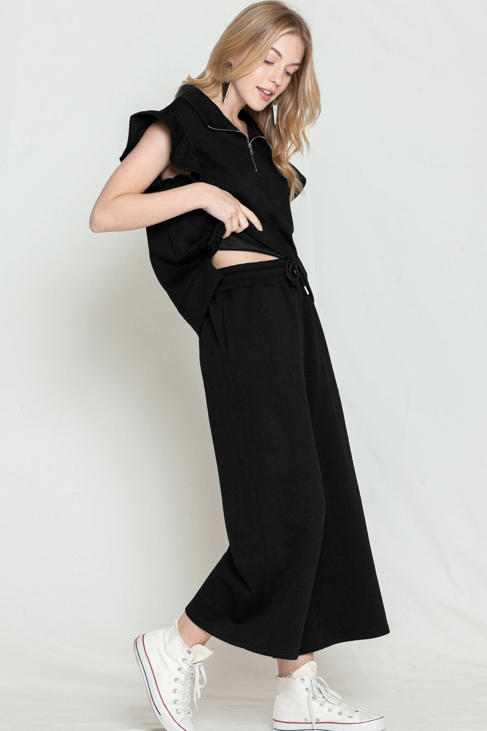 Model wearing black textured ruffle cap sleeve top and wide-leg pants set (front view).