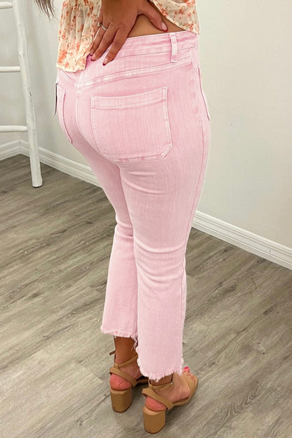 Model wearing high-waisted apricot pink crop jeans with multiple buttons and a raw edge, paired with strappy sandals.