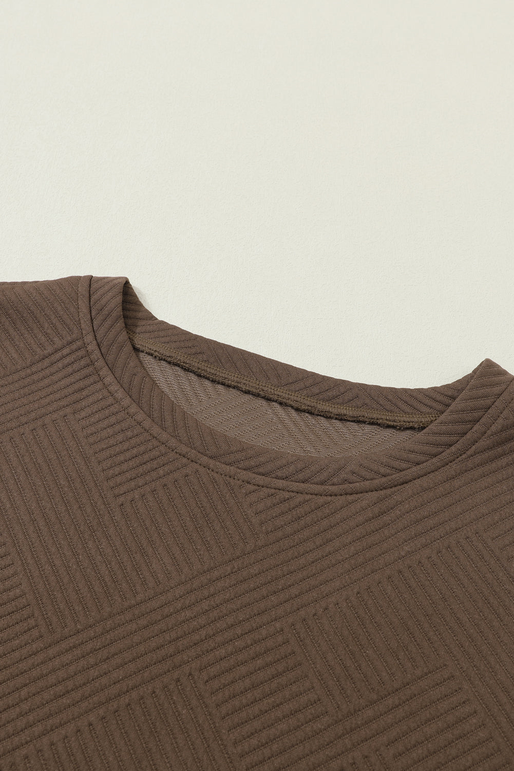 Close-up of the hemline on the black textured T-shirt.