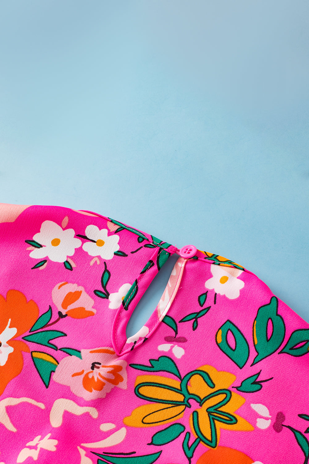 Close-up of the neckline and shoulder with flounce sleeve detailing on the pink floral blouse.