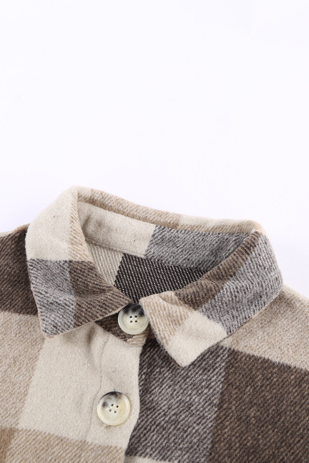 Close-up of the functional pockets on the front of the khaki plaid shacket.