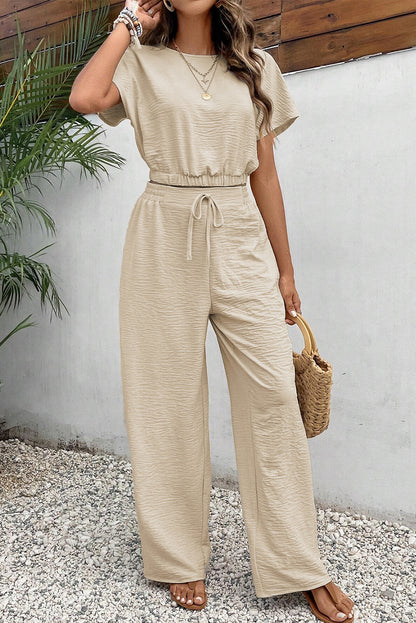 Close-up of the high-waisted wide-leg pants in a beige crinkled set.