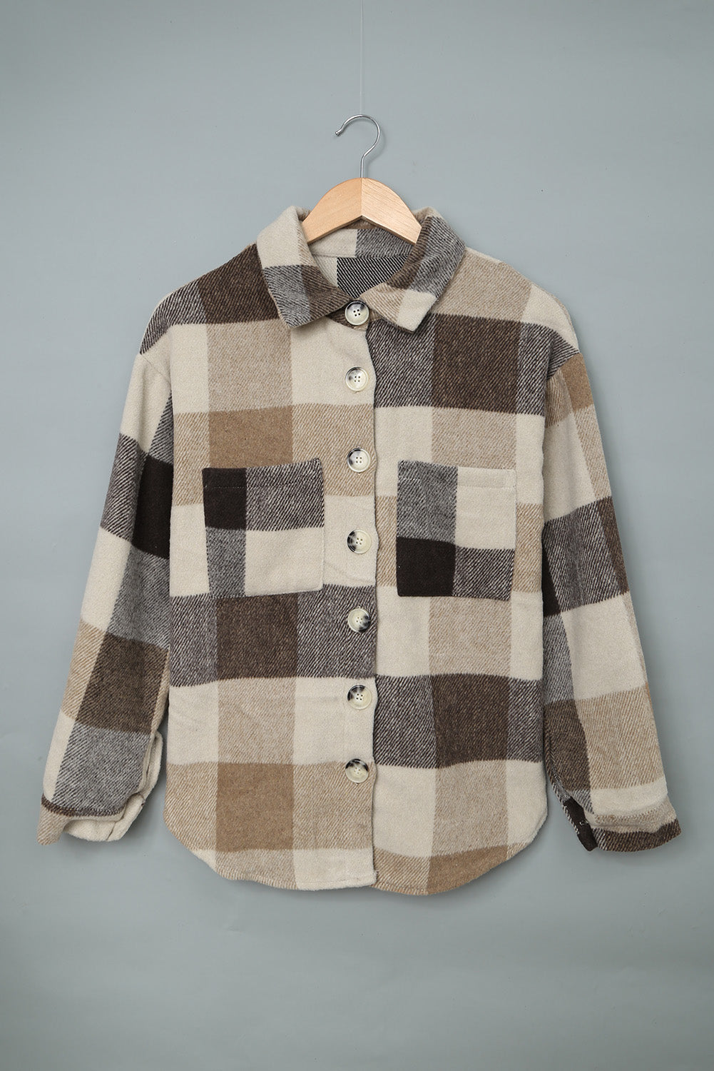 Khaki plaid color block buttoned shacket hanging neatly on a hanger.