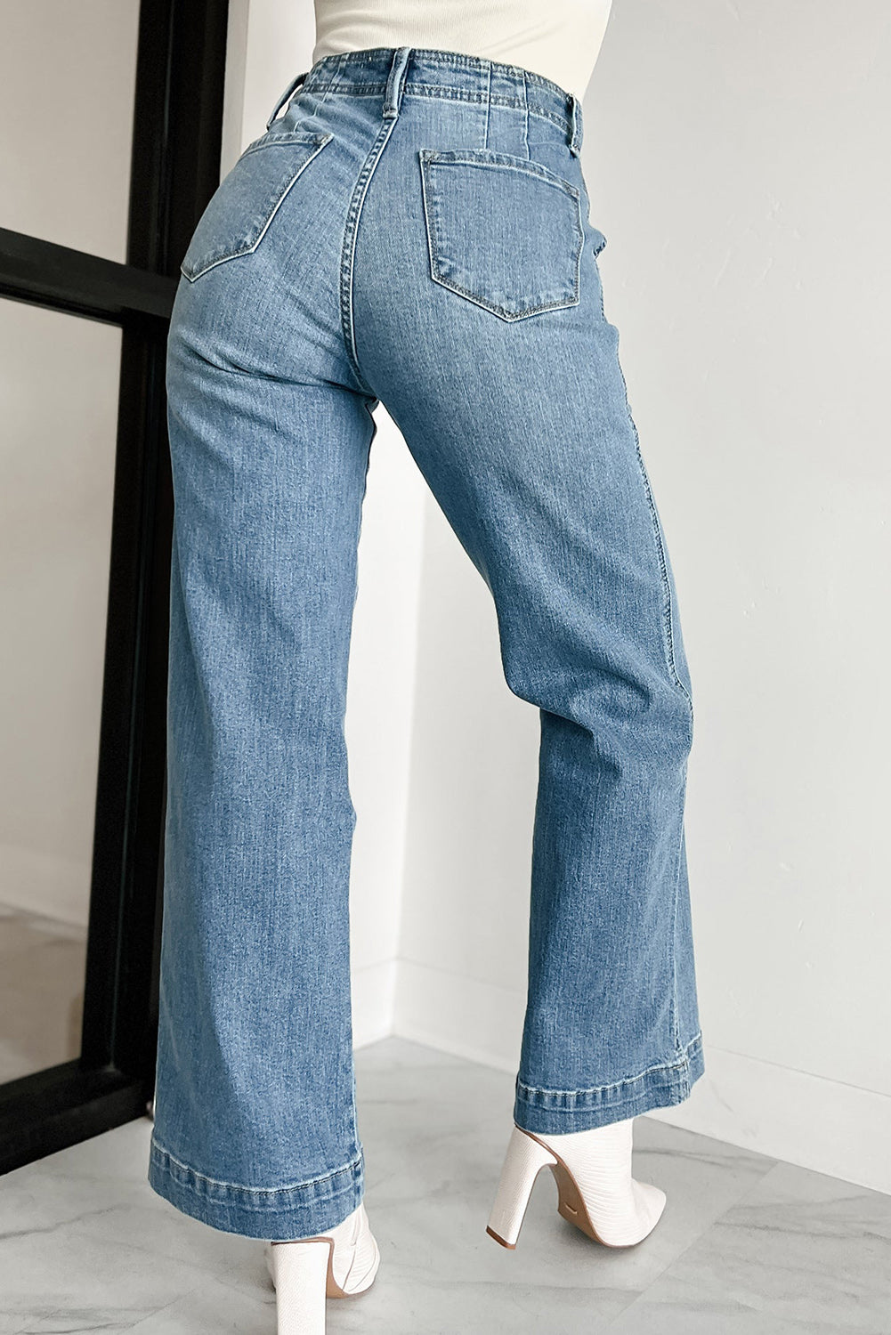 Close-up of the dusk blue wash and multi-button closure on the high waist of the jeans.