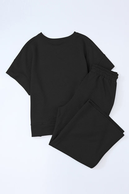 Black textured T-shirt and drawstring pants set folded neatly for easy storage.