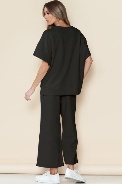 Close-up of black textured fabric on T-shirt and drawstring pants set.