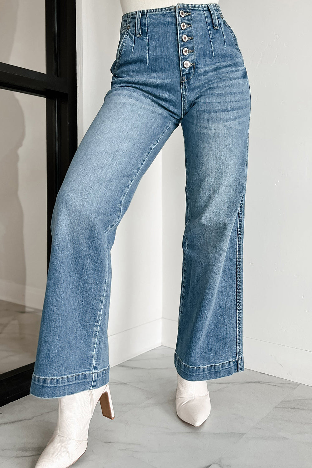 Model walking confidently in dusk blue multi-button waist wash straight leg jeans.