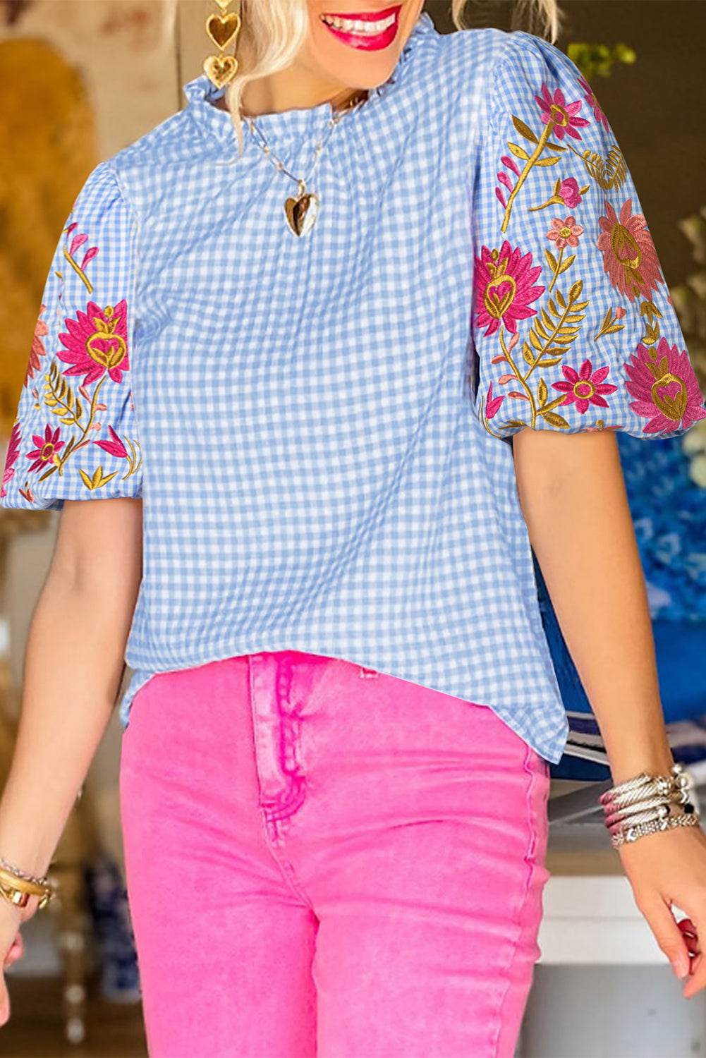 Model wearing a light blue gingham blouse with puff sleeves and floral embroidery, showcasing the romantic and chic style (front view).