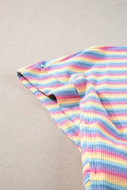 Close-up of the model smiling and twirling in the pink striped rainbow tee and pants set.