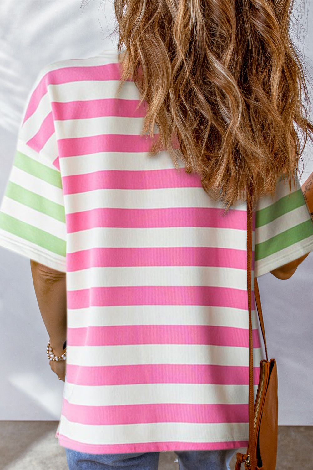 Close-up of the side slits on the hem of the pink striped t-shirt.