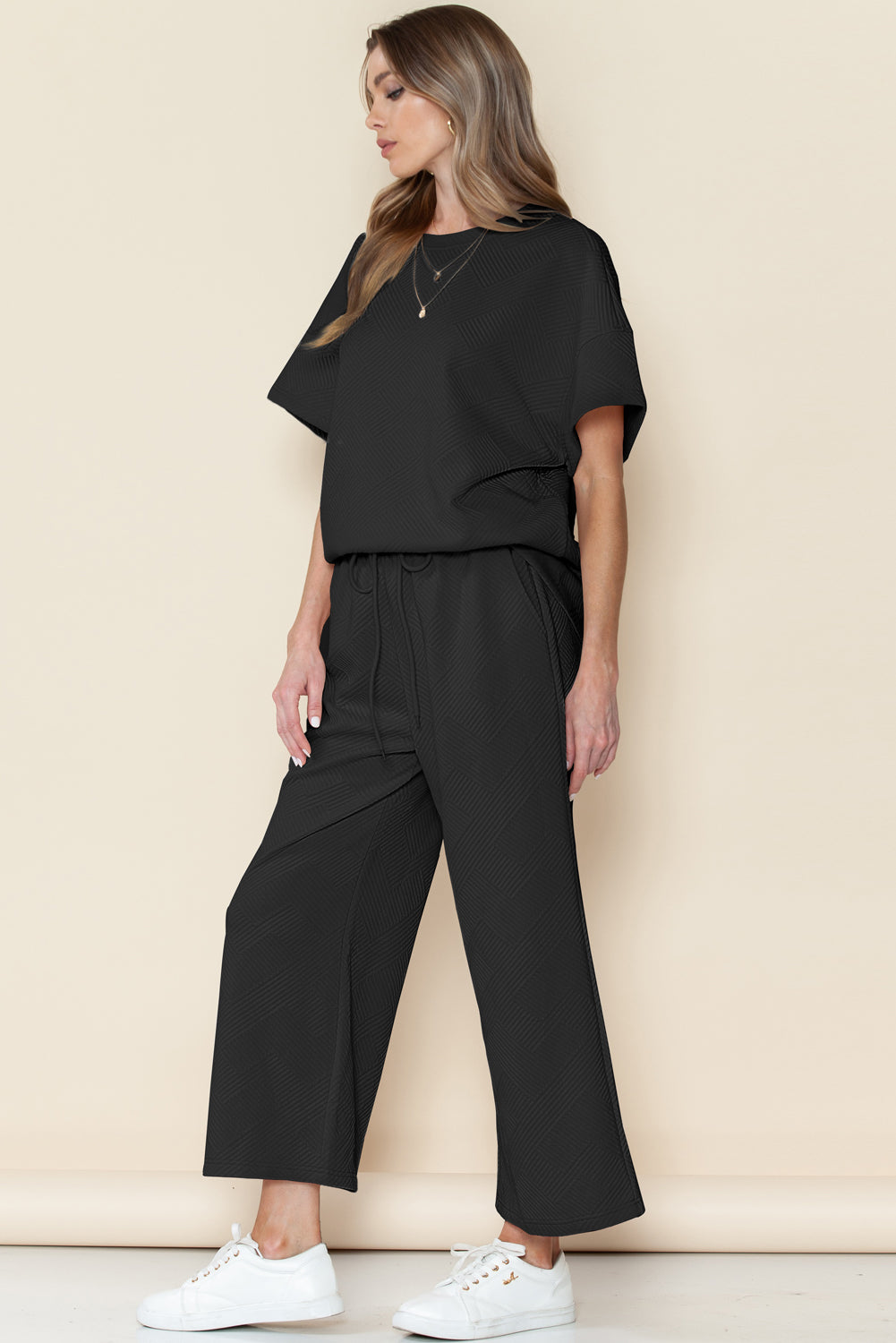 Model wearing black textured T-shirt and drawstring pants set (relaxed fit, front view).