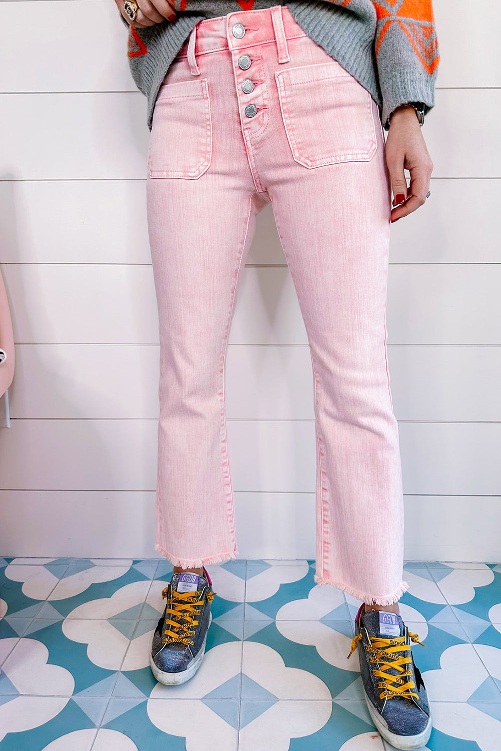 Close-up of several decorative buttons on a pair of apricot pink crop jeans.