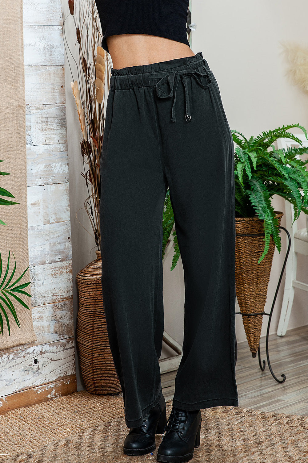 Black high-waisted wide-leg pants styled with a trendy crop top.