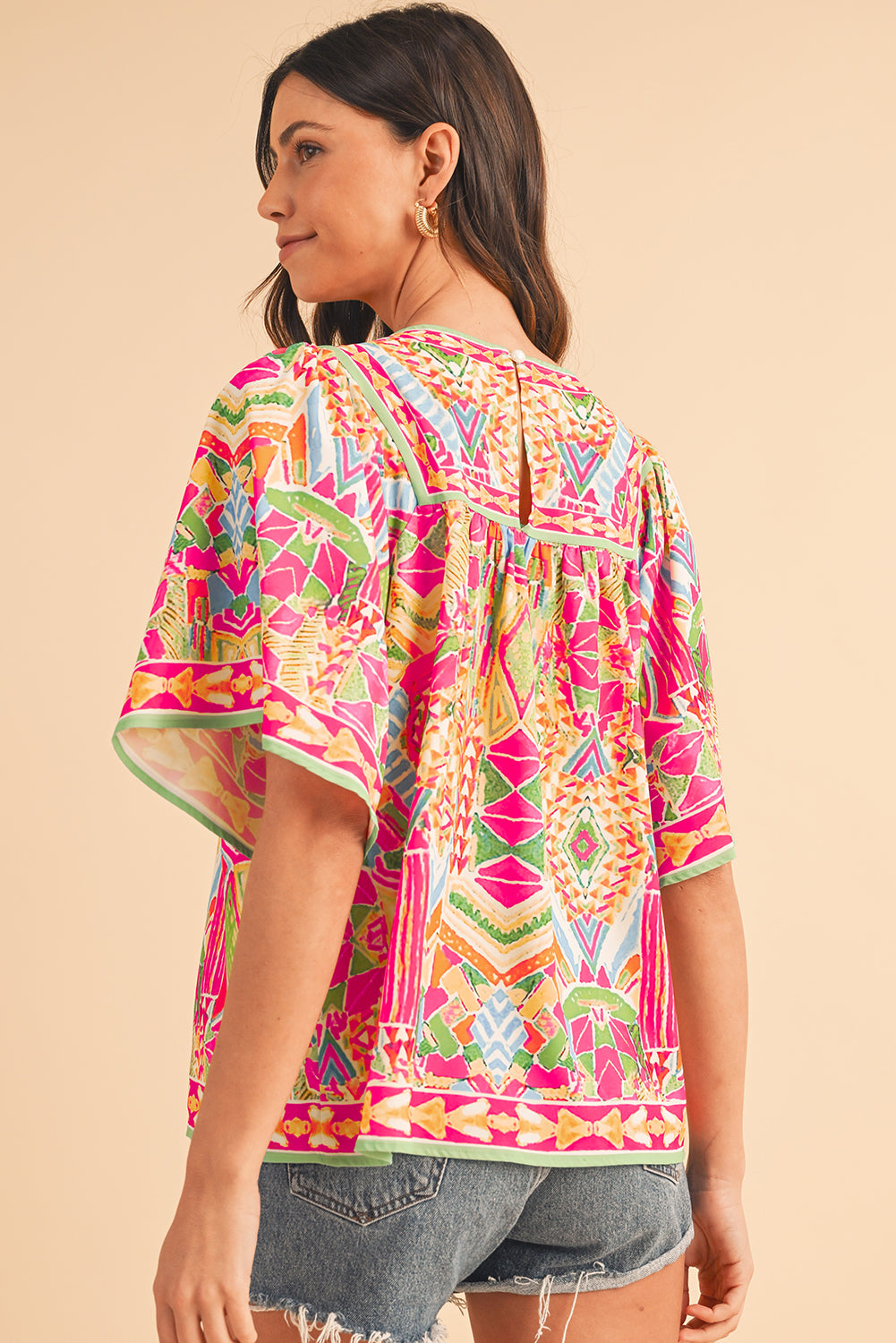 Model confidently walking in the orange geometric print blouse with jeans (casual outfit).