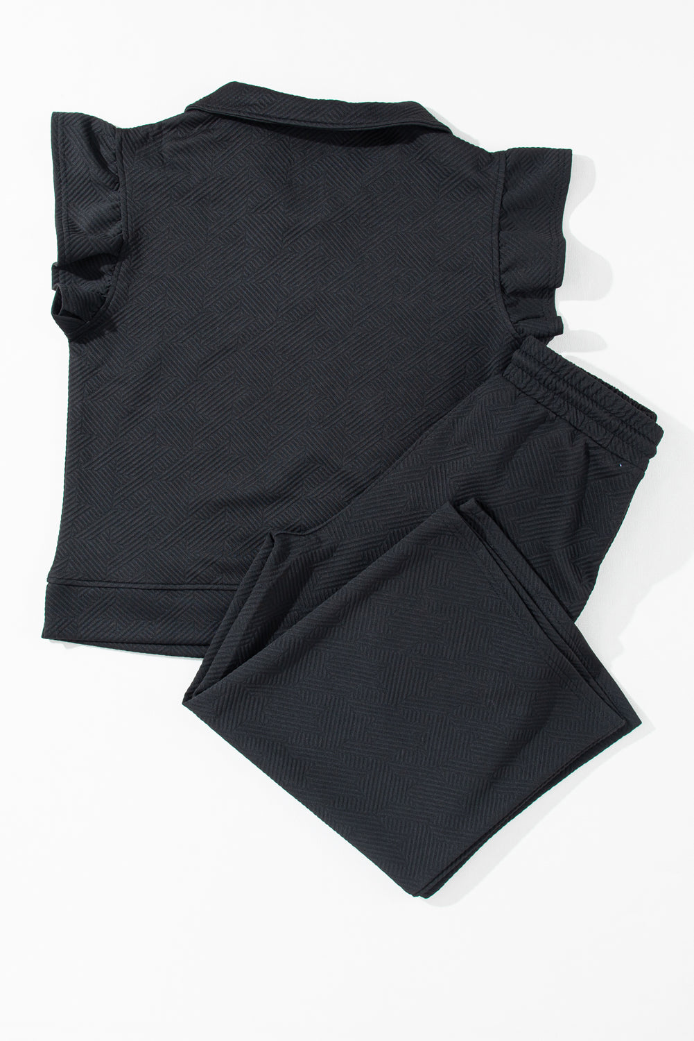 Close-up of the hemline on the black textured ruffle cap sleeve top.