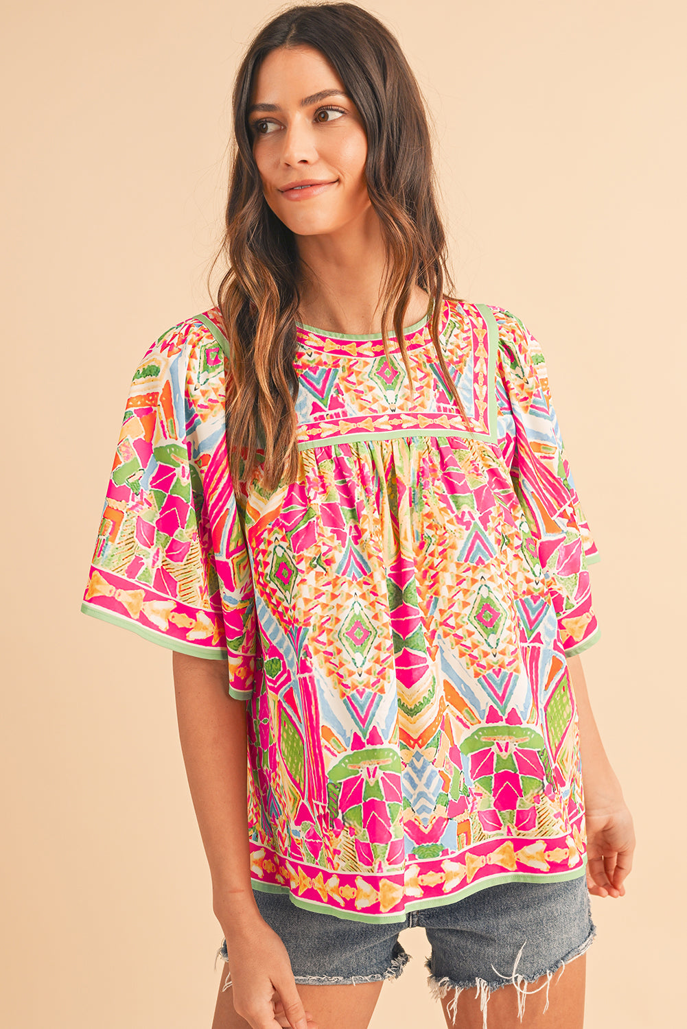 Close-up of the model accessorizing the orange geometric print blouse with a necklace (text overlay: "Accessorize Your Way").