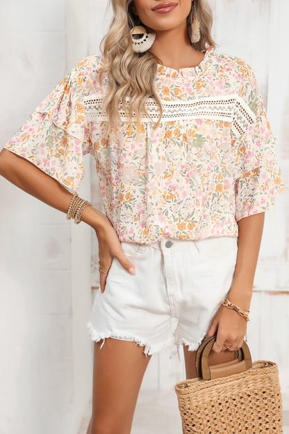 Model wearing a flowy multicolor floral blouse with wide sleeves (front view).