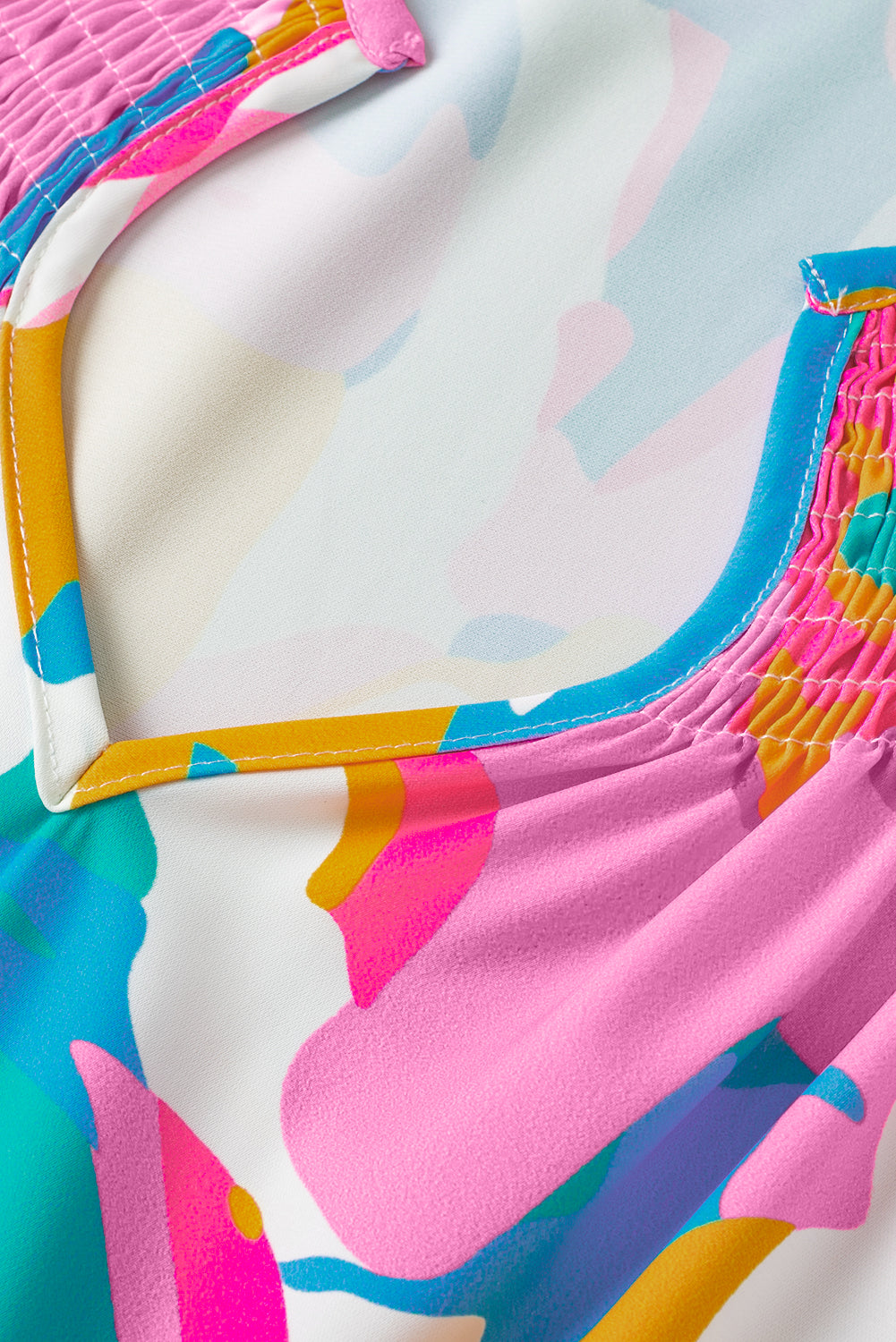 Close-up of a hand holding the ruffled neckline of the multicolour abstract print blouse