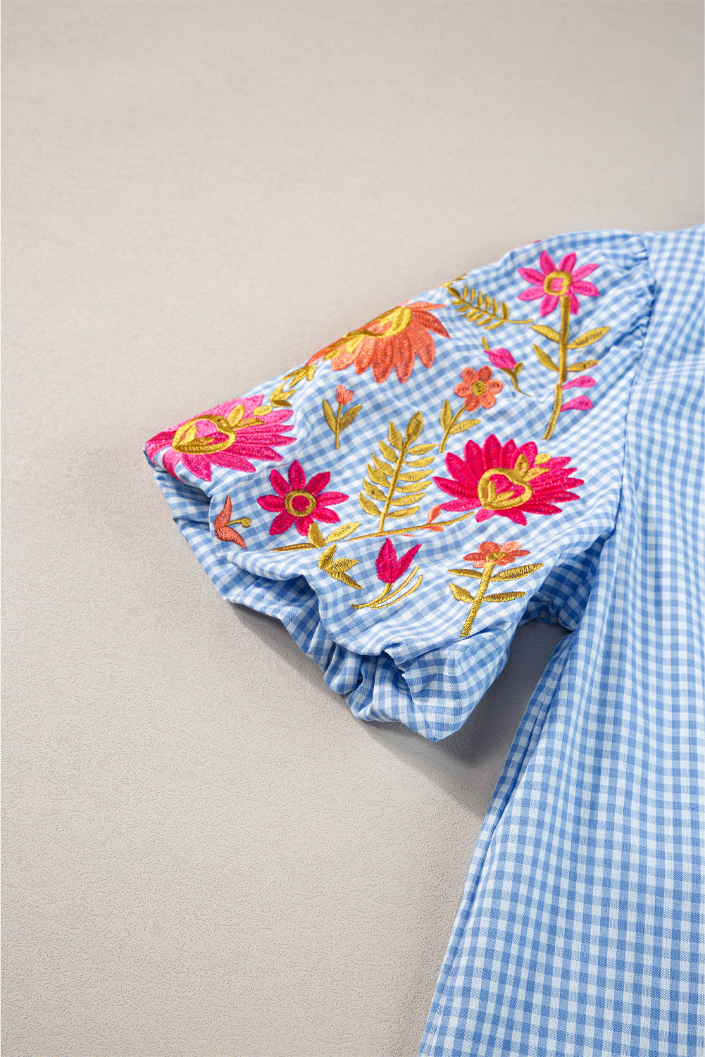 Model with arms raised, showcasing the fit and sleeve length of the light blue gingham blouse.