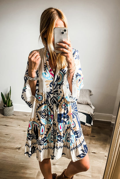 Model sitting comfortably wearing the white ethnic print dress, highlighting its relaxed fit.