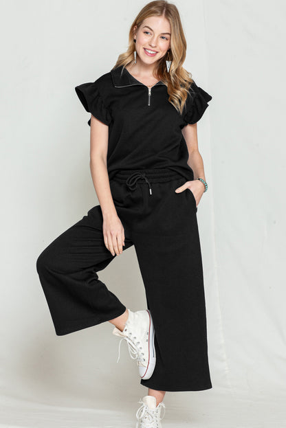 Black textured ruffle cap sleeve top and wide-leg pants set styled for a casual outing.