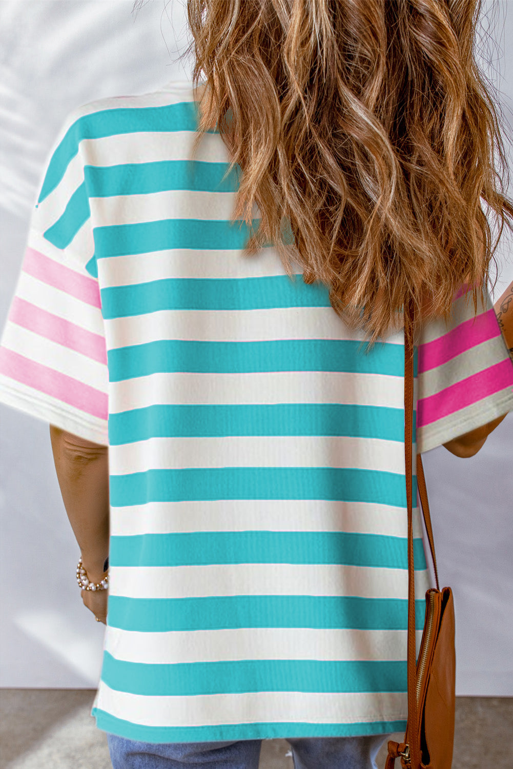 Model wearing the pink striped t-shirt tucked into jeans for a casual look.