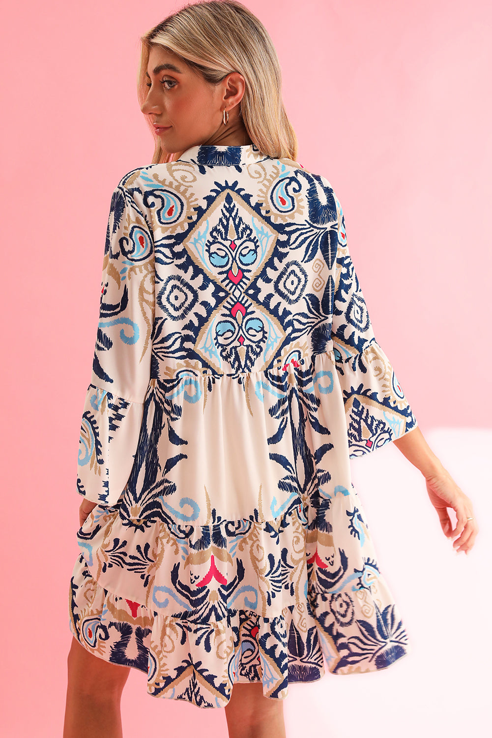 Model wearing a white ethnic print boho button tiered mini dress, showcasing the flowy silhouette and bohemian style (front view).